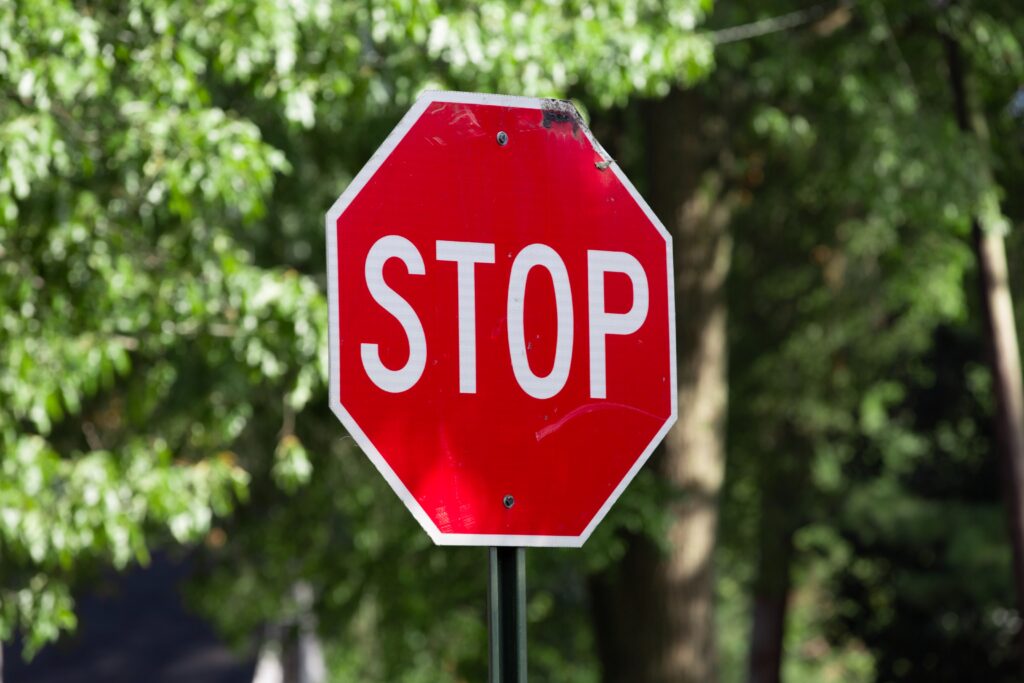 Red stop sign with green tree background. 